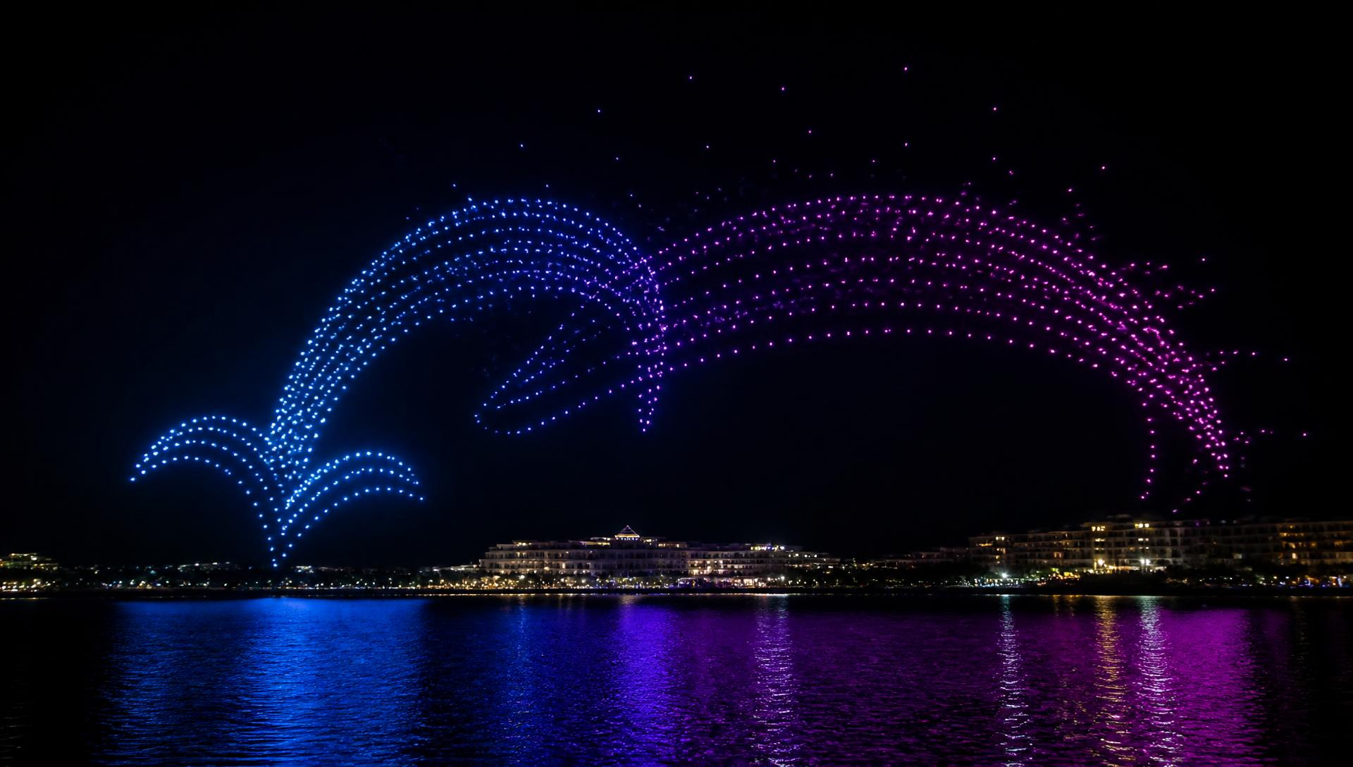 A large synchronized drone light show forming a glowing blue and magenta arc above a Bahamian waterfront at night